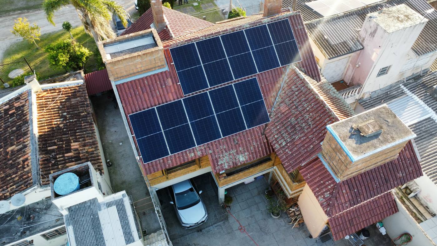 Vista aérea de painéis solares instalados em telhado de telhas cerâmicas de uma residência
