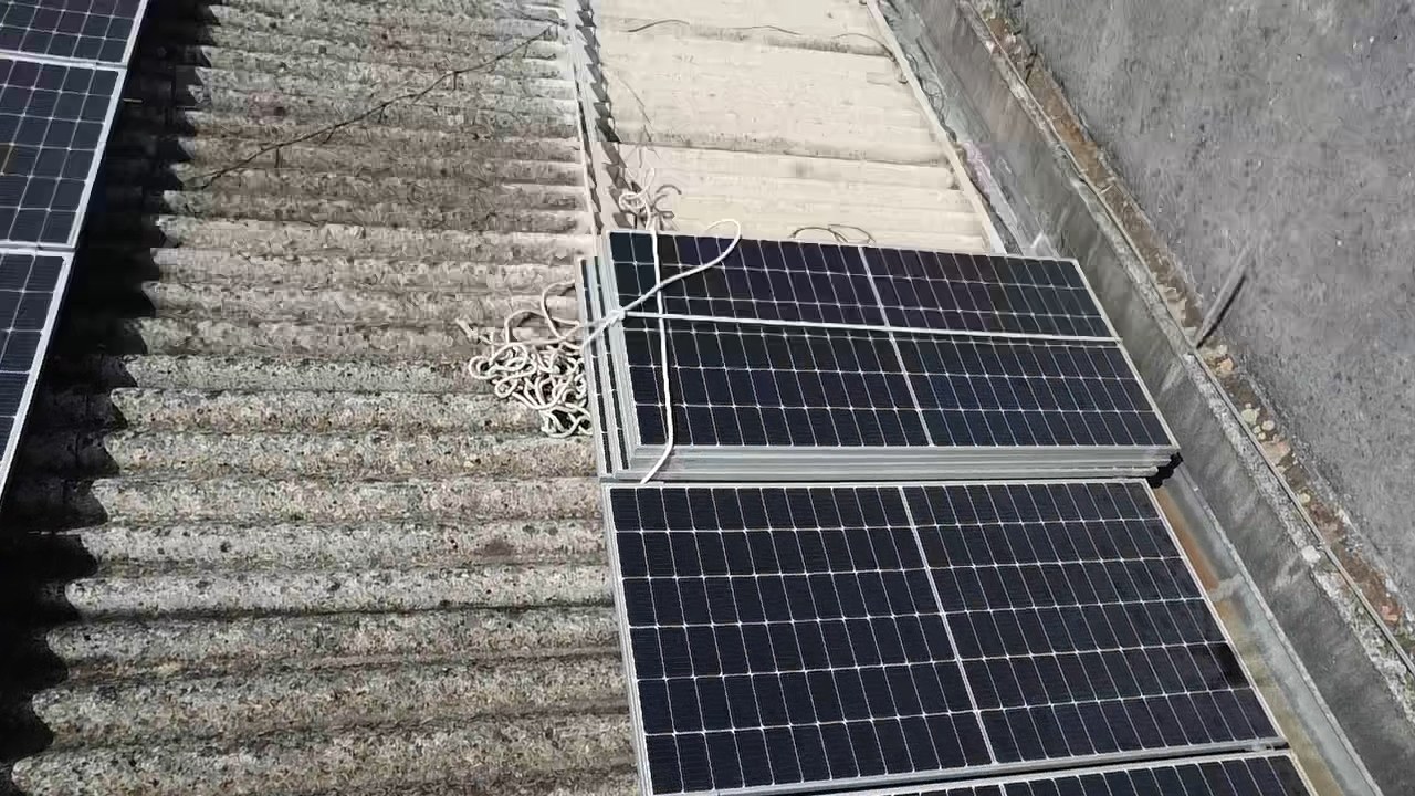 Detalhe anterior à intervenção: módulos solares e cabos sobre a cobertura